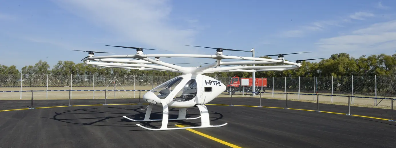 velicopter bianco cielo azzurro asfalto aereoporto piante sullo sfondo